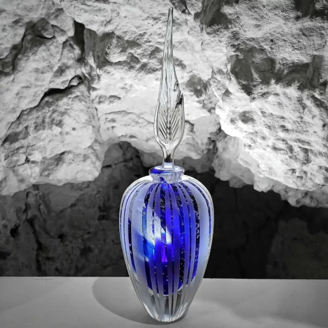 Flacon de haute précision : contient 100% de mystère"Ce flacon en verre soufflé a tout pour intriguer : un bleu profond, des stries élégantes et un bouchon qui donne envie de vérifier s’il ne contient pas un secret bien gardé. Élixir rare ? Potion magique ? Eau du robinet embouteillée avec style ? On ne le saura jamais.Ce qui est sûr, c’est qu’il brille sous les projecteurs… et qu’il n’a pas fini de faire parler de lui.#VerreSoufflé #FlaconDeMystère #Artisanat #FaitMain #ObjetDeConversation