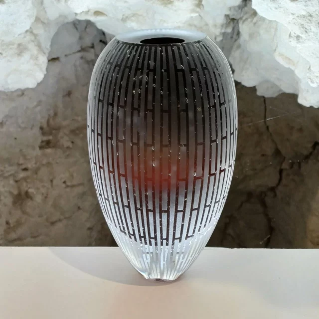 Prisonnier de la transparence.
Condamné à perpète dans un décor géométrique, sans espoir de libération anticipée.
Silencieux, droit, il attend qu’un rayon de lumière lui fasse la belle.
Pas de barreaux à limer ici, juste du verre à admirer.
Et à défaut d’évasion, il a gagné sa place sur le devant de la scène.

#verre #souffleurdeverre #verreartisanal #vase #verredart #verriere #glassart #artisandeverre #designverre #faitmain #amboise #objetsdesign #artverrier #glassblowing